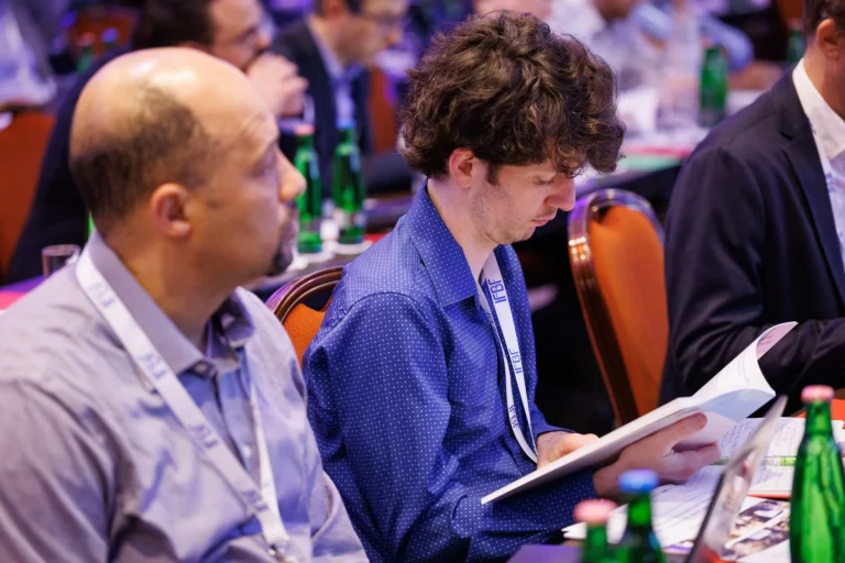 Delegates reading the IFBF Book of Papers during a session